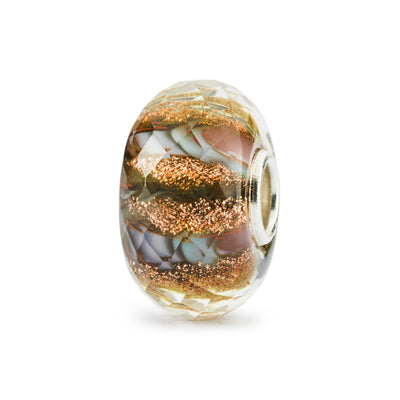 The Sun & Soil bead is made of glass with a silver core, cointaining a faceted cut shape in orange and brown colors containing traces of glimmer.